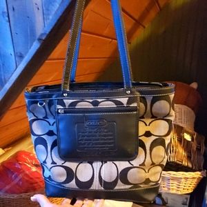 A black and gray coach designer handbag with wallet attached slightly used.